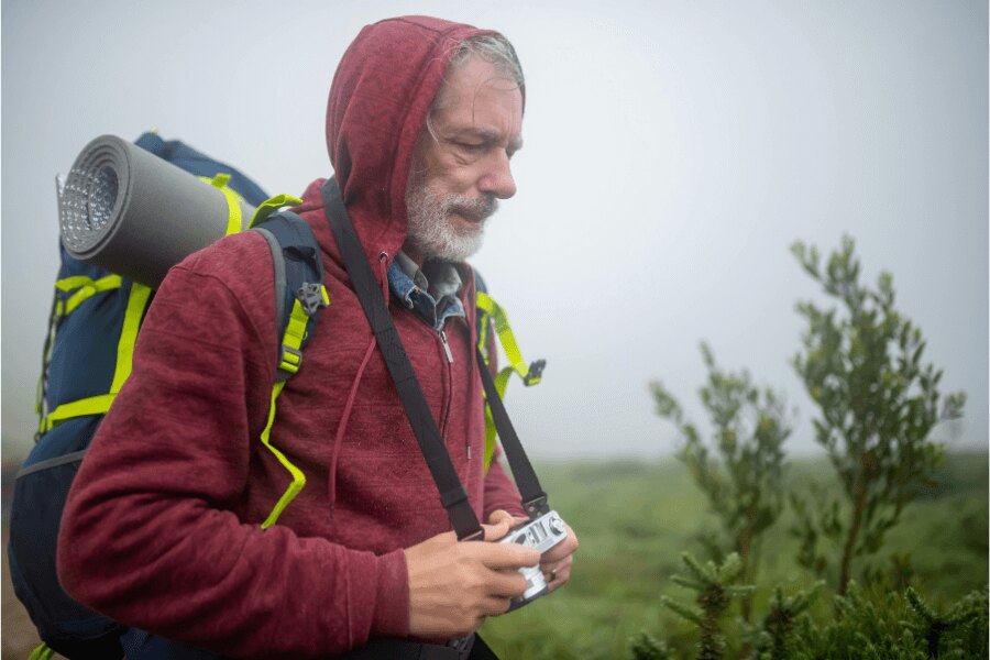 Muž v outdootovém oblečení trekuje v mlze. Zdroj: https://www.pexels.com/cs-cz/foto/muz-fotoaparat-tramp-pesi-turistika-7787466/