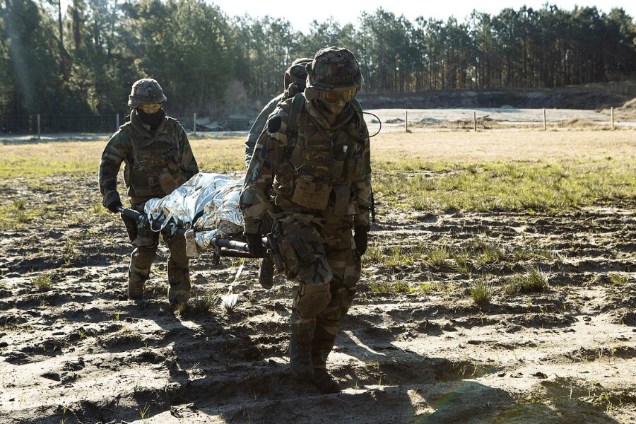 Vojáci nesou zraněného v nosítkách přikrytého izotermickou fólií. Zdroj: https://upload.wikimedia.org/wikipedia/commons/4/48/Dutch_Troop_Attack_160322-M-BZ307-198.jpg