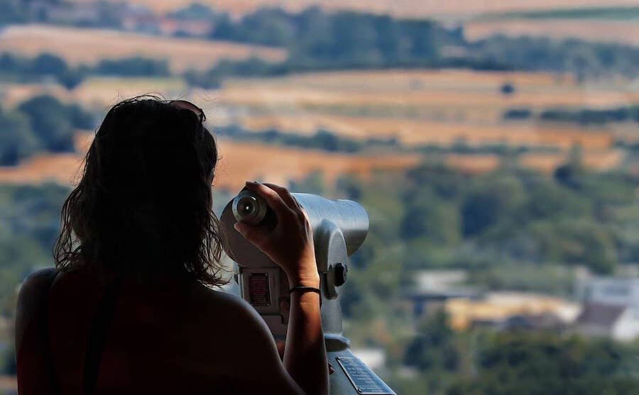 Žena sledující výhled na krajinu dalekohledem